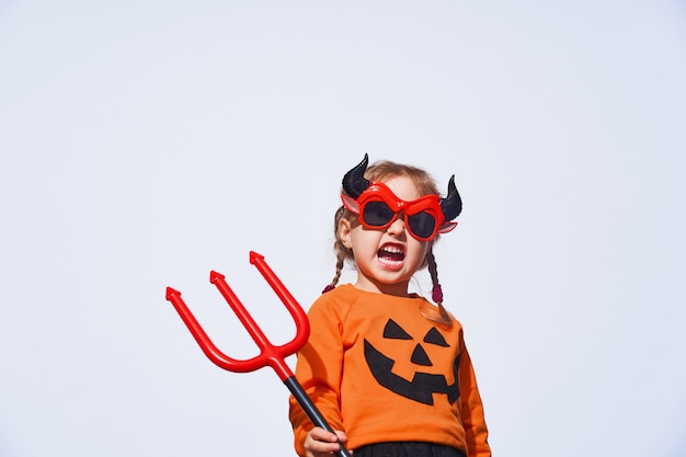 Un enfant en costume de diable avec un trident et des cornes