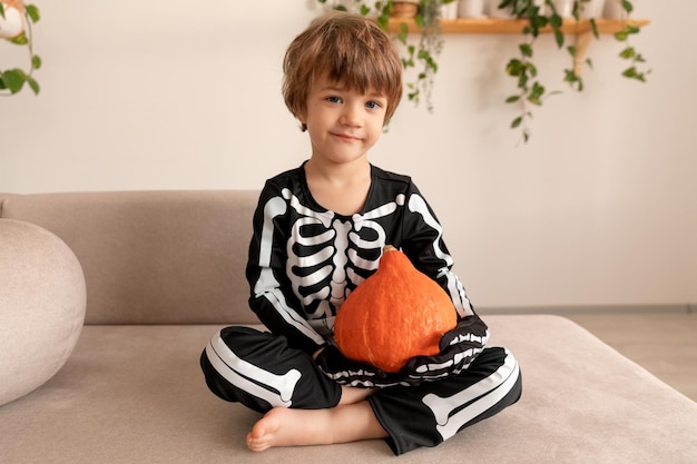 un enfant en costume d'halloween est assis avec une citrouille