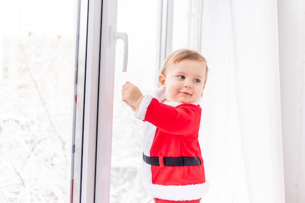 Enfant en costume de Santa sur le rebord de la fenêtre, le concept de nouvel an et de Noël