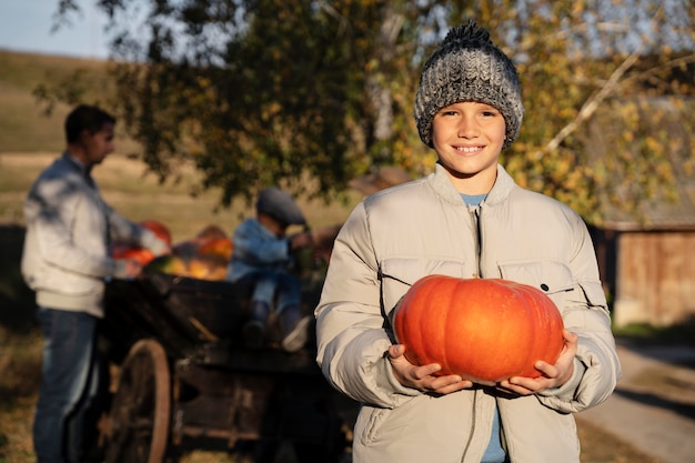 Photo enfant de coup moyen tenant une citrouille