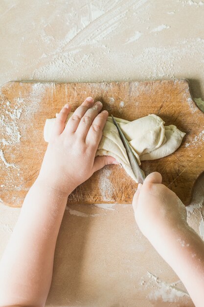 Un enfant coupe la pâte crue