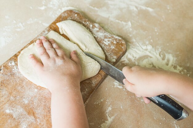 Un enfant coupe la pâte crue