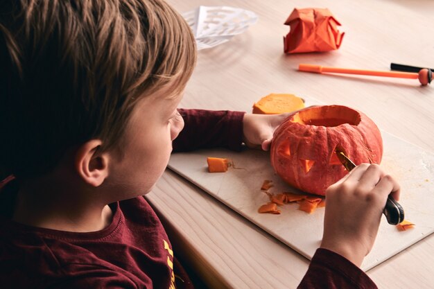 enfant avec un couteau à découper une citrouille ou une citrouille-lanterne. Maman passe du temps avec son fils ensemble.