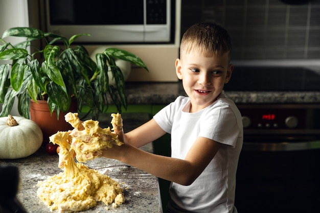 Enfant cuisinant dans la cuisine. Le garçon aide à faire de la pâte aux cookies. Mec méchant. Activité intérieure.