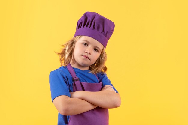 Un enfant cuisinier prépare de la nourriture sur un fond de studio isolé Des enfants cuisinent Un adolescent avec un tablier et un chapeau de chef prépare un repas sain