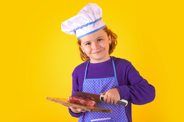 Enfant cuisinier tenir une planche à découper avec de la viande steak de boeuf et un couteau