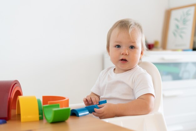 Enfant curieux blond jouant avec des figures géométriques en bois concept d'éducation des enfants à la maison