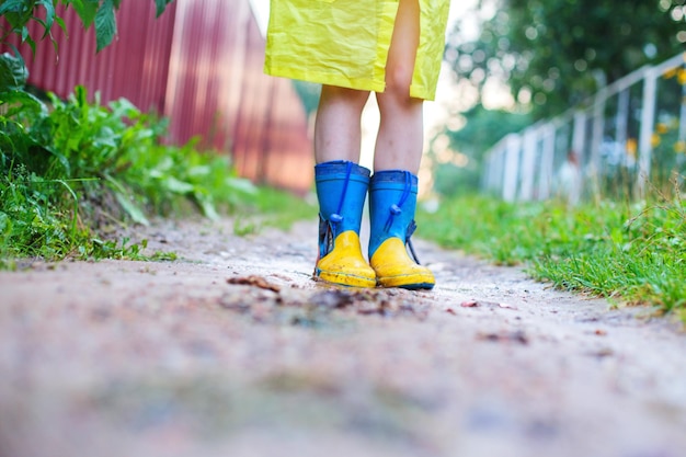 Enfant dans des bottes en caoutchouc marchant les pieds d'un enfant en plein air dans une botte en caoutchouc