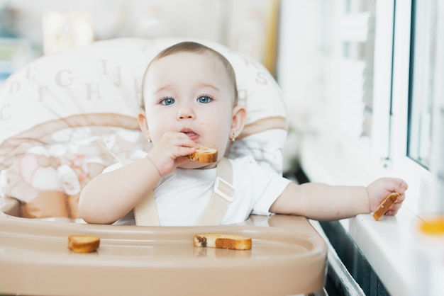 Un enfant dans une chaise haute mangeant un cracker aux raisins secs