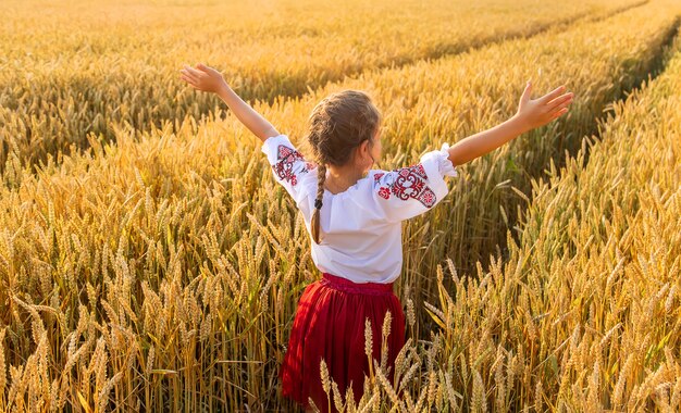 Enfant dans un champ de blé. Dans vyshyvanka, le concept de la fête de l'indépendance de l'Ukraine. Mise au point sélective. Enfant.