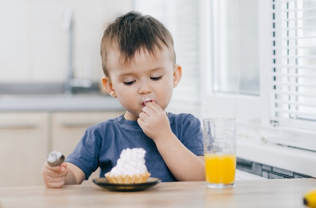 L'enfant dans la cuisine mangeant un gâteau à la crème