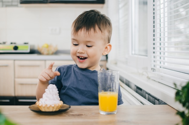 L'enfant dans le doigt de la cuisine touche le gâteau, va manger le prochain jus