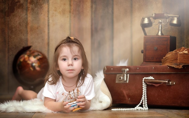 Un enfant dans un intérieur rétro et un vieux téléphone sont assis par terre. Un petit enfant voyageur dans des décorations vintage. Un enfant voyageur appelle par téléphone.