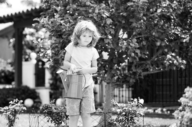 Enfant dans le jardin fleuri portrait d'un enfant travaillant dans le jardin