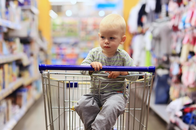 enfant dans le magasin sur le chariot d'épicerie est un petit client