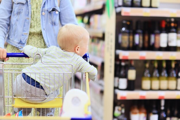 enfant dans le magasin sur le chariot d'épicerie est un petit client