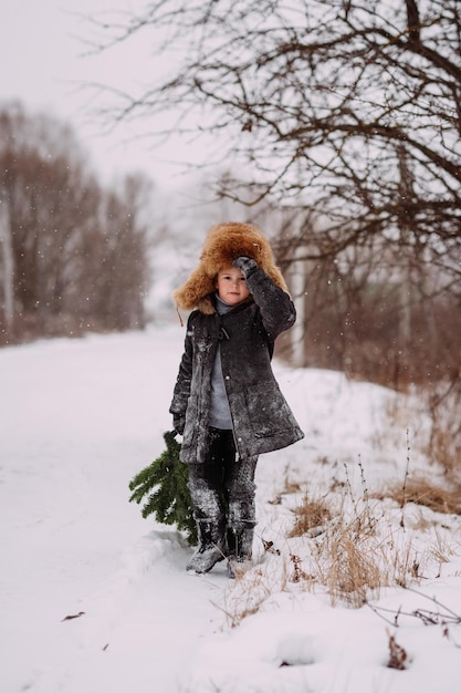 Un enfant dans la neige ramène un sapin de Noël de la forêt 3121