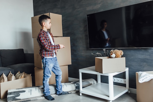 Enfant dans un nouvel appartement, attendant de regarder des films Avec des boîtes de déballage