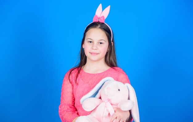 Enfant dans des oreilles de lapin de lapin Chasse aux œufs Vacances en famille Petite fille avec un jouet de lièvre Fête de printemps Joyeuses Pâques Moments heureux Profiter de chaque instant Grand plaisir heureux petit enfant