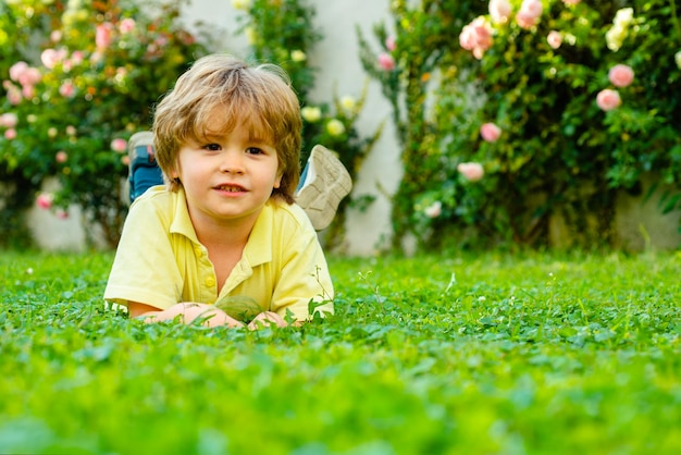 Enfant dans un parc ou un jardin en plein air Enfant de printemps allongé sur l'herbe Promenade d'un garçon d'été Adaptation pour enfants