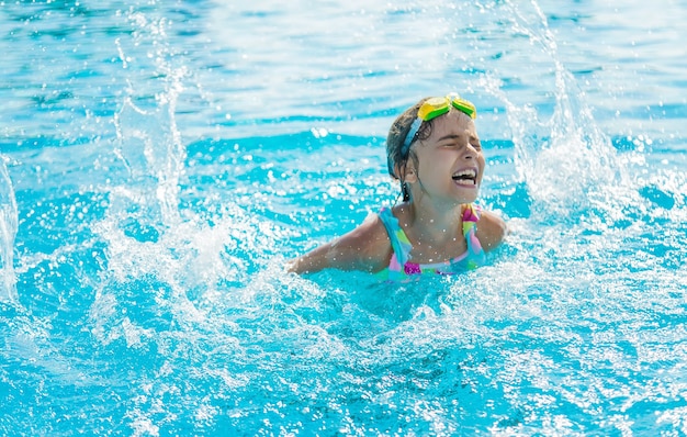 Un enfant dans la piscine éclabousse de l'eau. Mise au point sélective. Enfant.