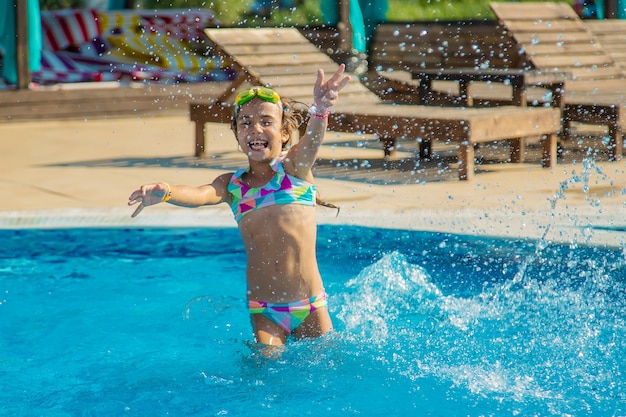 Un enfant dans la piscine éclabousse de l'eau. Mise au point sélective.