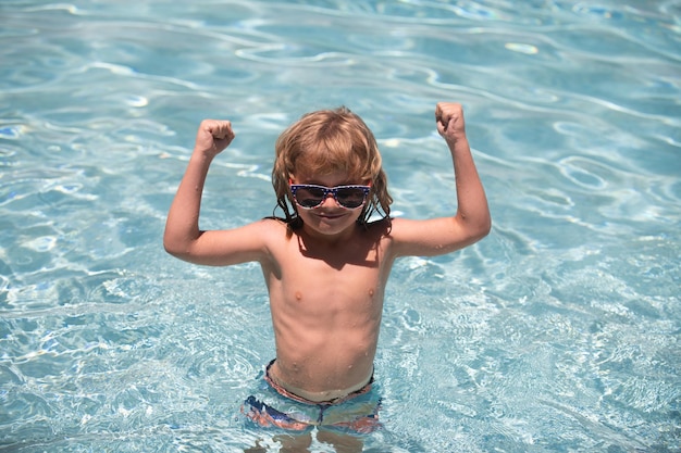 Enfant dans la piscine excité mignon petit garçon à lunettes de soleil dans la piscine en journée ensoleillée