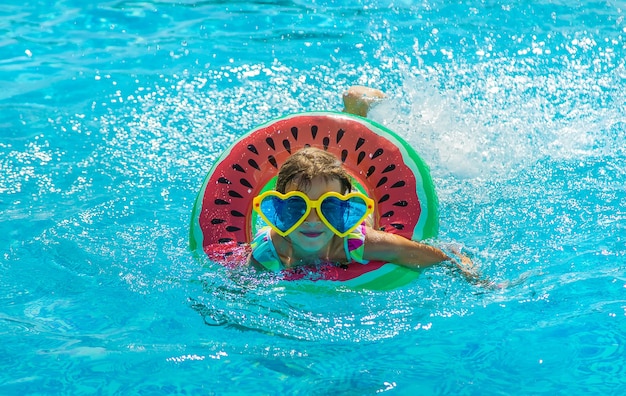 L'enfant dans la piscine nage en cercle. Mise au point sélective. Enfant.