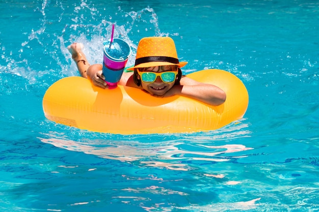 Enfant dans la piscine nageant sur un anneau gonflable enfant nageant avec un jouet d'eau flottant orange sain en plein air