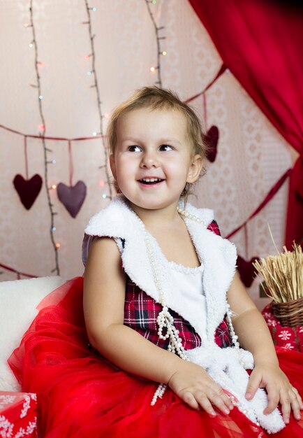 Enfant dans les vêtements du Nouvel An, passe du temps à l'arbre de Noël