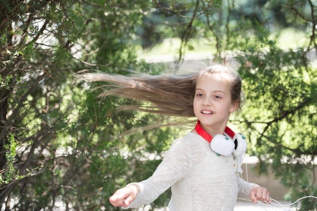 Enfant danseur avec de longs cheveux volants Enfant dansant sur de la musique dans un parc d'été