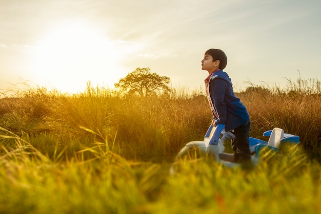 Enfant debout au milieu de la campagne, dans sa petite voiture regarde le chemin