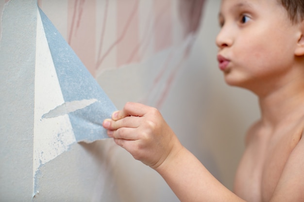 L'enfant déchire le papier peint