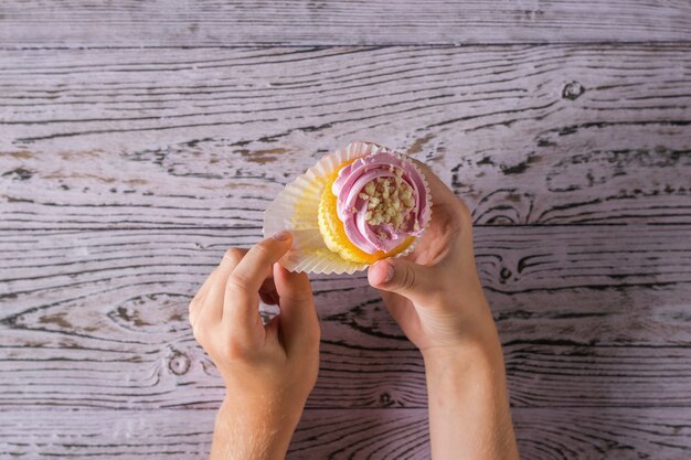 L'enfant déplie un petit gâteau fraîchement préparé sur une table en bois