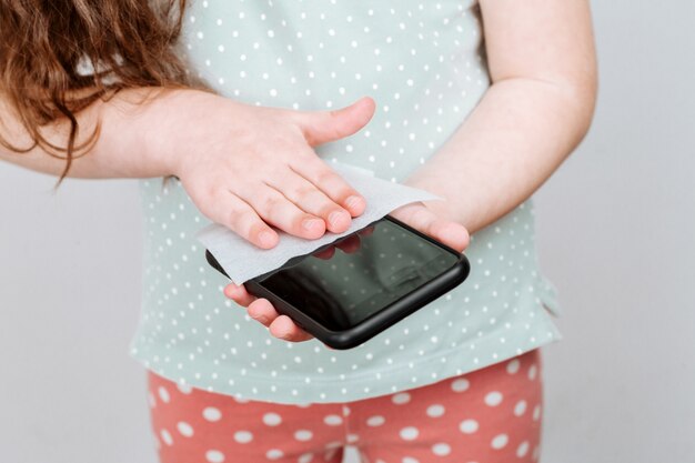 l'enfant désinfecte l'écran du téléphone.