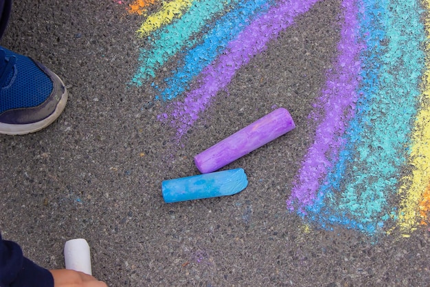 Un enfant dessine un arc-en-ciel sur l'asphalte Mise au point sélective