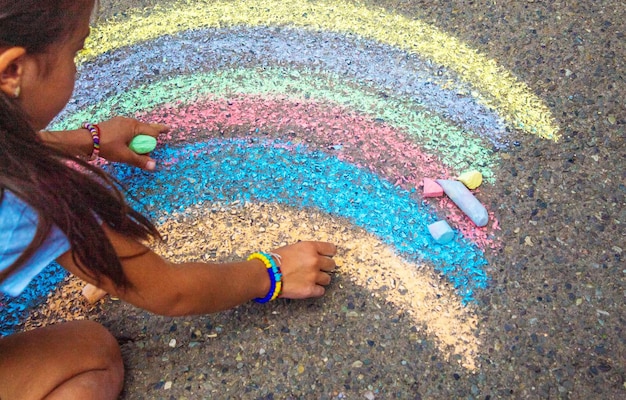 Un enfant dessine un arc-en-ciel sur l'asphalte Mise au point sélective