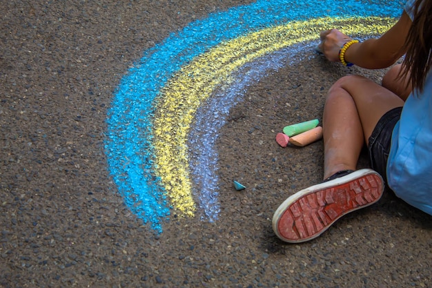 Un enfant dessine un arc-en-ciel sur l'asphalte Mise au point sélective