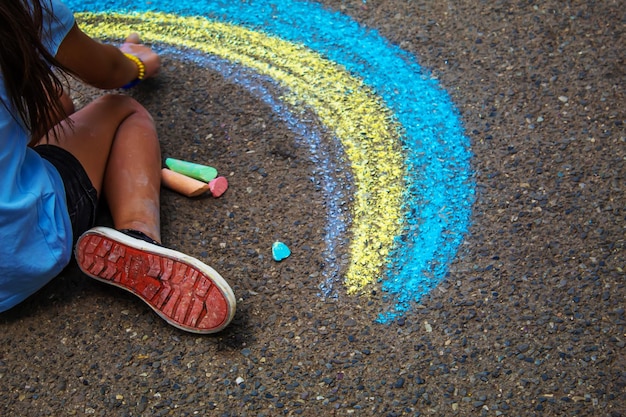 Un enfant dessine un arc-en-ciel sur l'asphalte Mise au point sélective