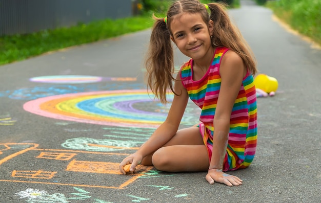 L'enfant dessine à la craie sur l'asphalte. Mise au point sélective.