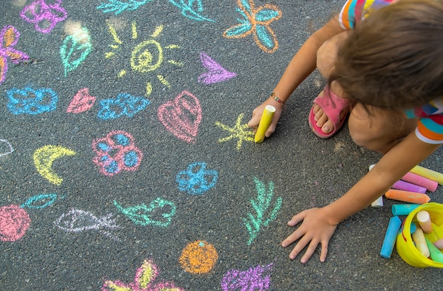 L'enfant dessine à la craie sur l'asphalte