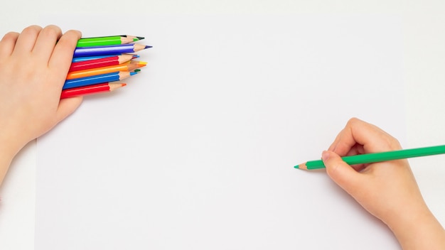 L'enfant dessine avec des crayons de couleur.