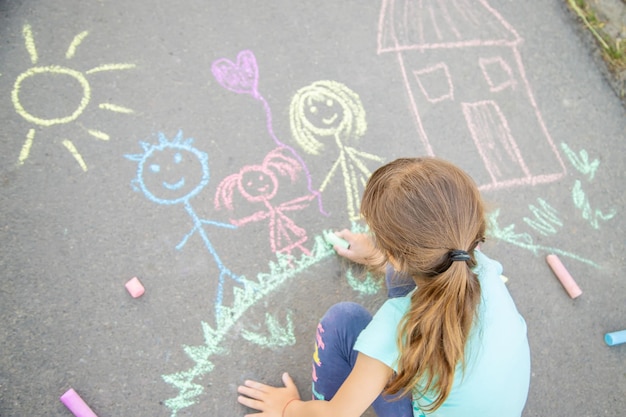 L'enfant dessine une famille sur le trottoir avec de la craie Mise au point sélective