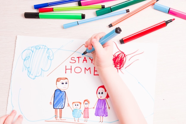 L'enfant dessine avec des feutres une famille et une maison sur papier rester à la maison concept