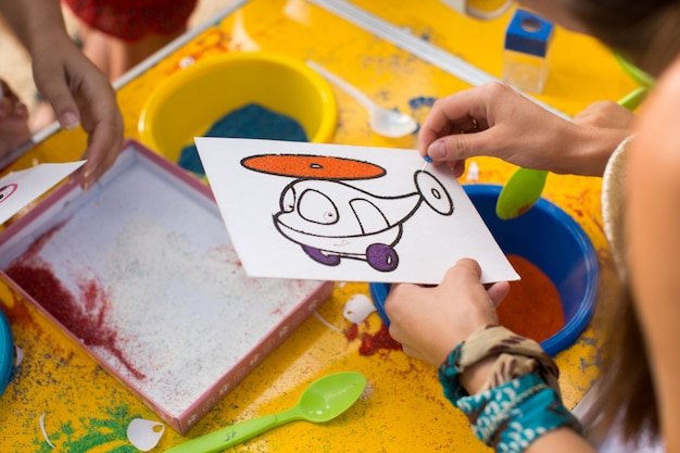 Un enfant dessine avec une image de sable coloré. Personnages de dessins animés.