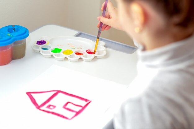 Enfant dessine la maison avec des aquarelles