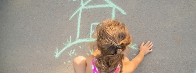 L'enfant dessine une maison à la craie. Mise au point sélective.