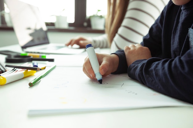 L'enfant dessine pendant que sa mère travaille avec un ordinateur portable