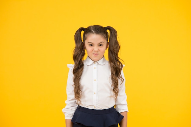 Enfant difficile. Adorable écolière. Écolière élève cheveux longs coiffure mignonne queues de cheval. Programme éducatif. Enseignement à domicile en visite à l'école ordinaire. Étude d'efficacité. Écolière expression émotionnelle.