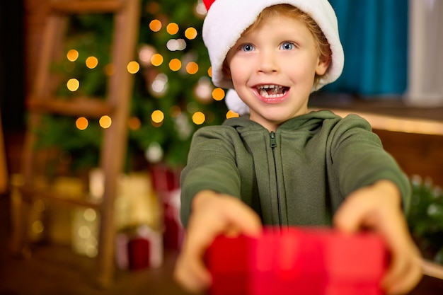 L'enfant donne un cadeau de Noël sur le fond d'un arbre du Nouvel An